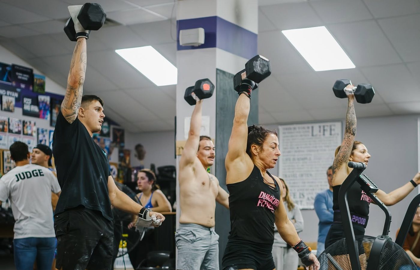 Members pressing dumbbells overhead during a workout