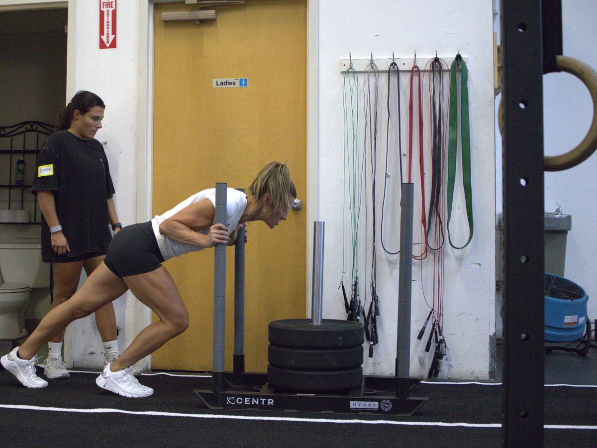An athlete driving a loaded sled down the track