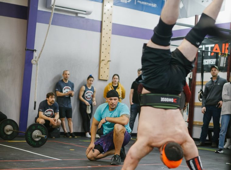 Members cheering a teammate through a handstand walk